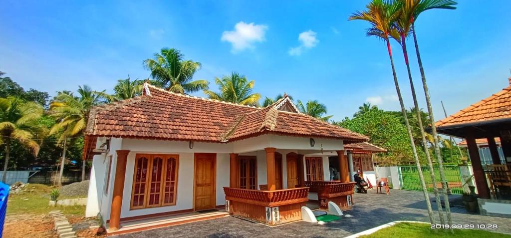 a small house with a tiled roof and palm trees at Breeze Backwater Homes in Cochin