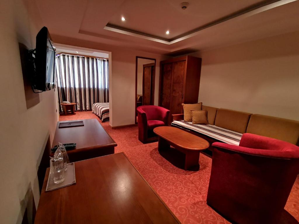 een hotelkamer met een bank en een tafel bij Garni Hotel BaMBiS in Podgorica