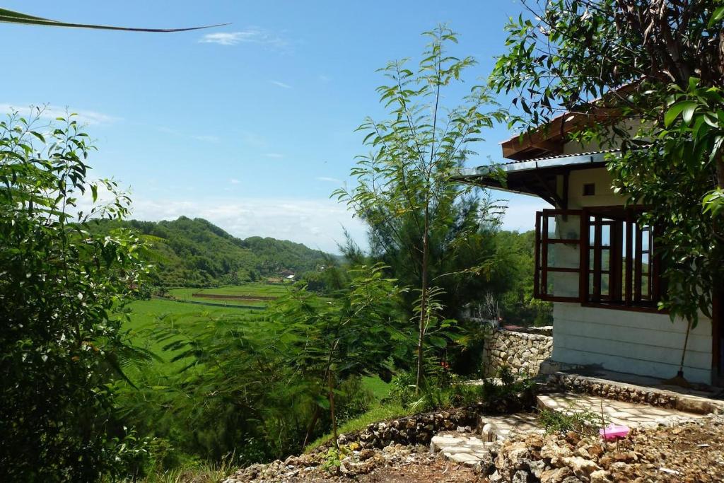 una casa con vistas a un campo verde en Fam Sugiono Cottage, en Kemadang