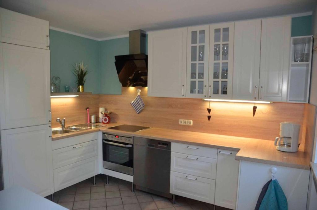 a kitchen with white cabinets and a sink at Ferienwohnung Biedermann in Schönwald