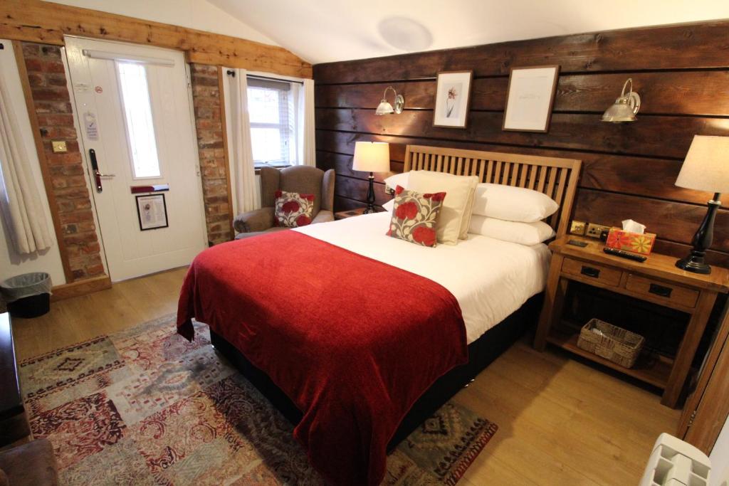 um quarto com uma cama com um cobertor vermelho em Boutique Garden Lodge @ The Larches em Wolverhampton