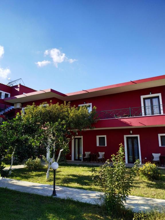 un edificio rosso con un albero di fronte di Ekaterini Apartments a Gouviá