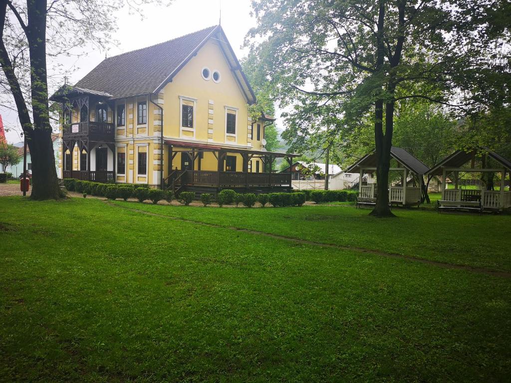 a large yellow house on a green lawn at Dofteana Park in Leorzeni