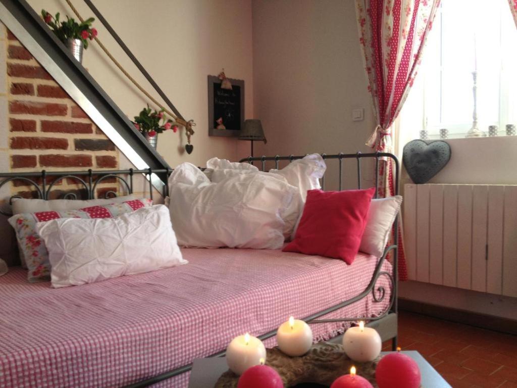 a bedroom with a bed with white and red pillows at Le Grand Gîte in Dorengt