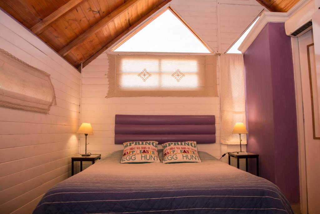 1 dormitorio con 1 cama con 2 almohadas y ventana en Cabañas La Maria Lourdes en Tafí del Valle