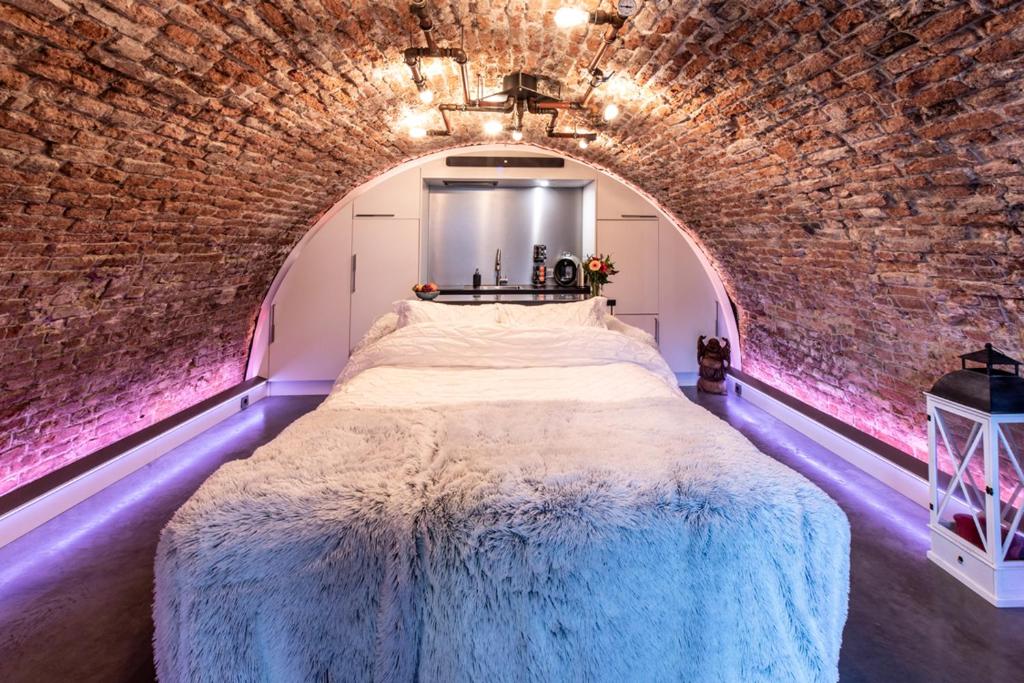 a bedroom with a large bed in a brick wall at UKI-Hotel in Utrecht