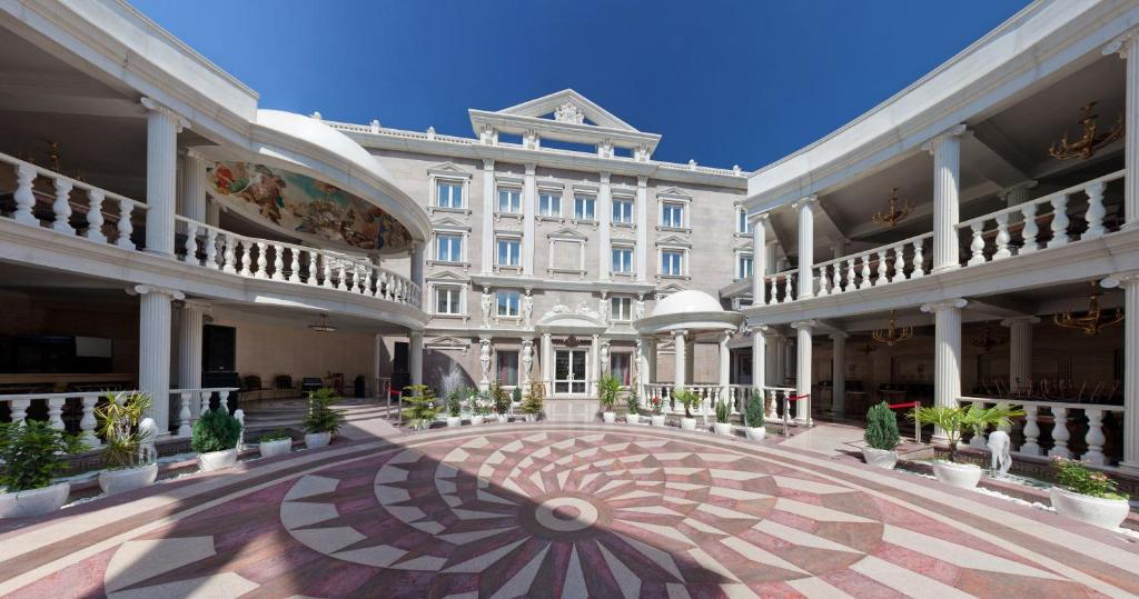 a large white building with a courtyard with potted plants at Villa Arte Hotel in Vladivostok