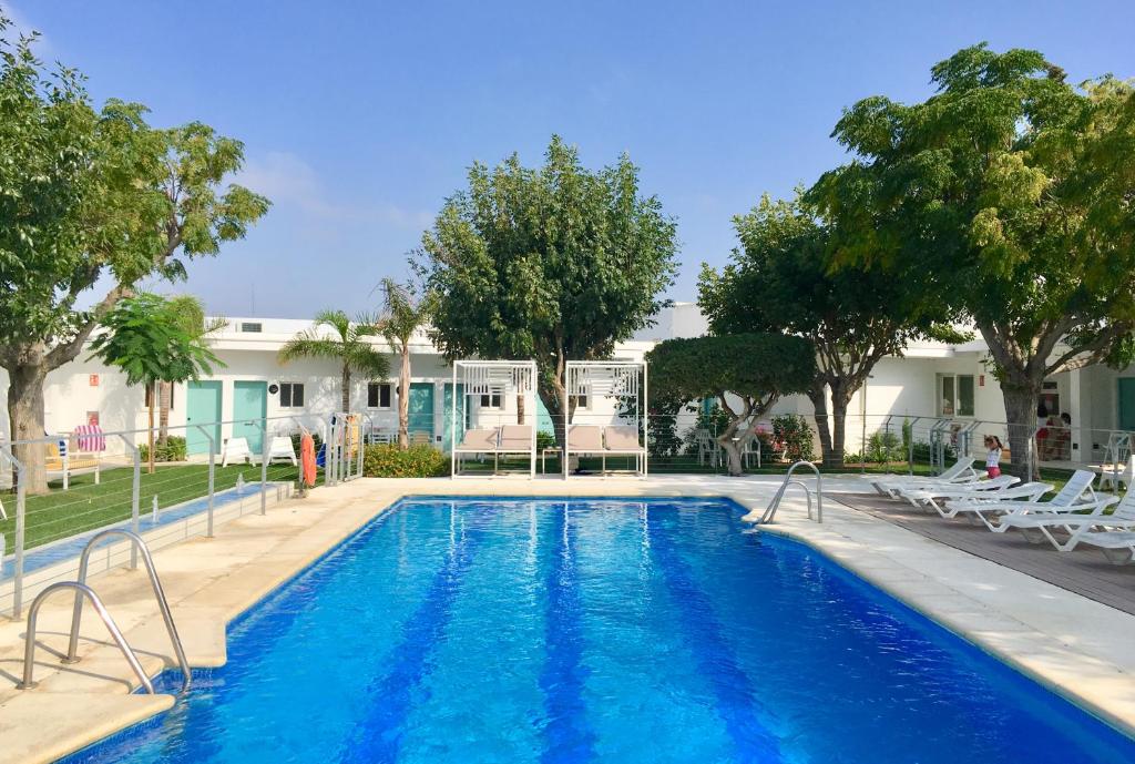 a swimming pool with chairs and a house at Hostal Las Cumbres in Conil de la Frontera