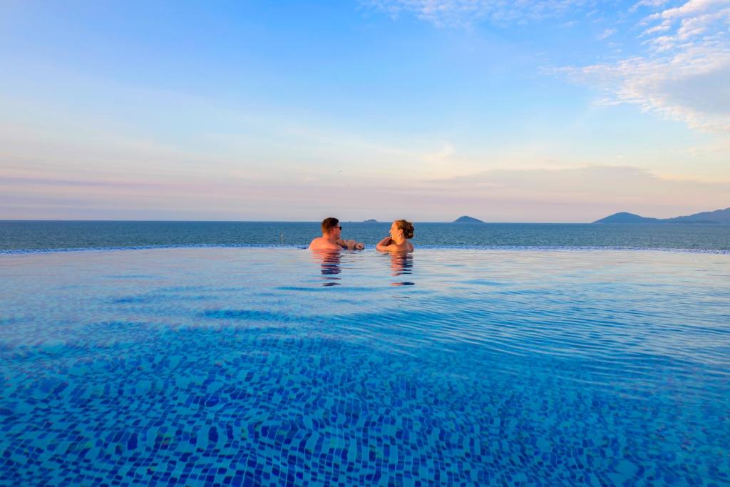 two people standing in the water in the ocean at Fivitel Hoi An Hotel in Hoi An