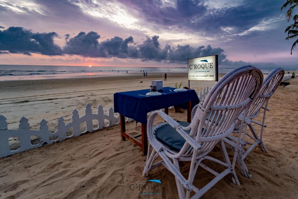 2 sillas y una mesa en la playa en C Roque Beach Resort, en Colva