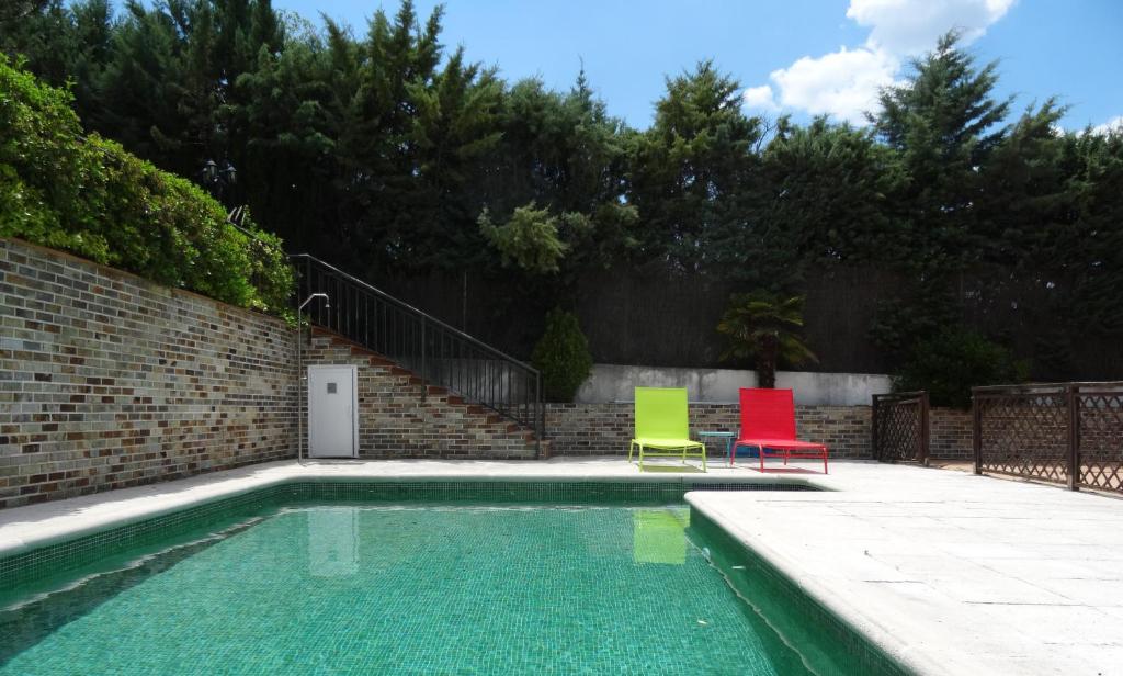 two colorful chairs sitting next to a swimming pool at BArcoiris B&B - Adults Men only - SOLO PARA HOMBRES in Torrelodones