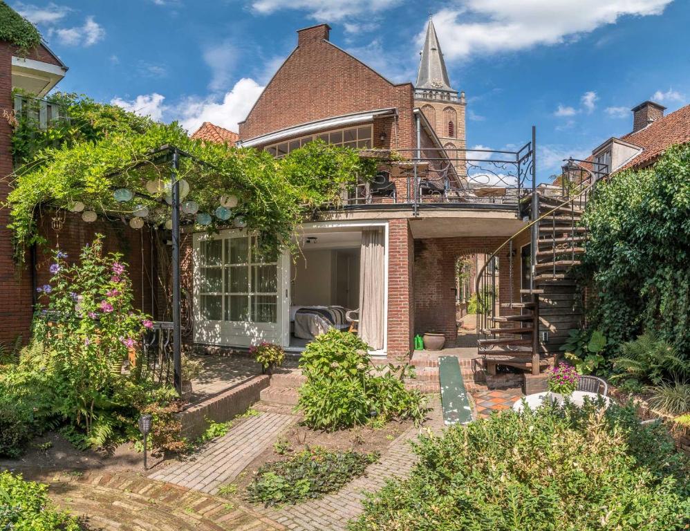 an exterior view of a brick house with a church at Hart van Lochem in Lochem