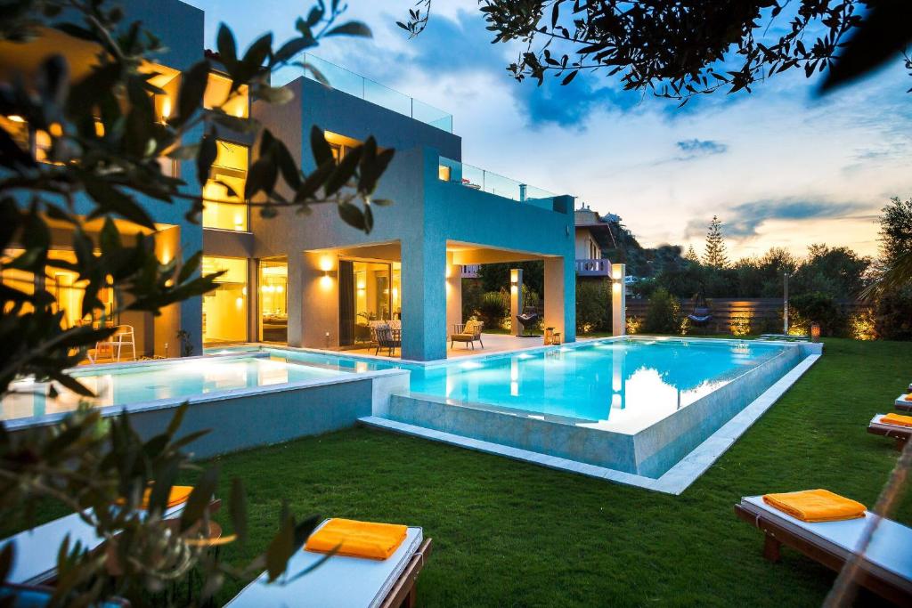 une grande maison avec une piscine dans une cour dans l'établissement Sissy Luxury Villa Chania, à Platanias