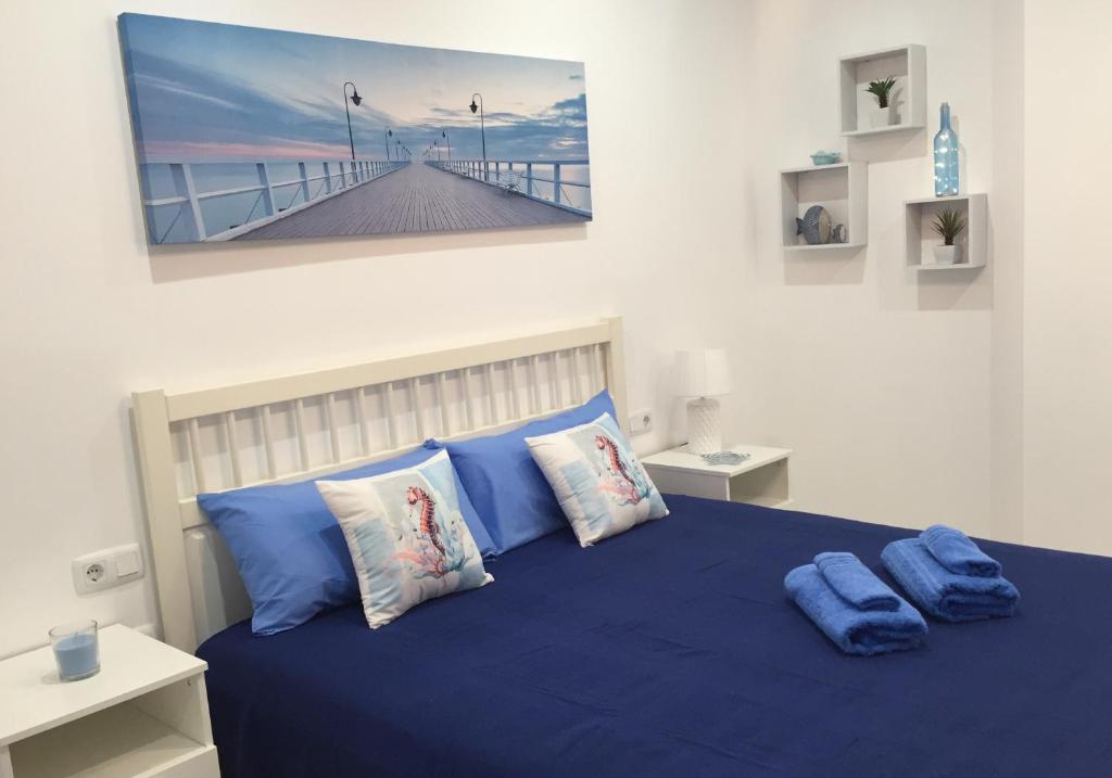 Un dormitorio con una cama azul con una foto en la pared en Casa Alejandro II, en Tarajalejo