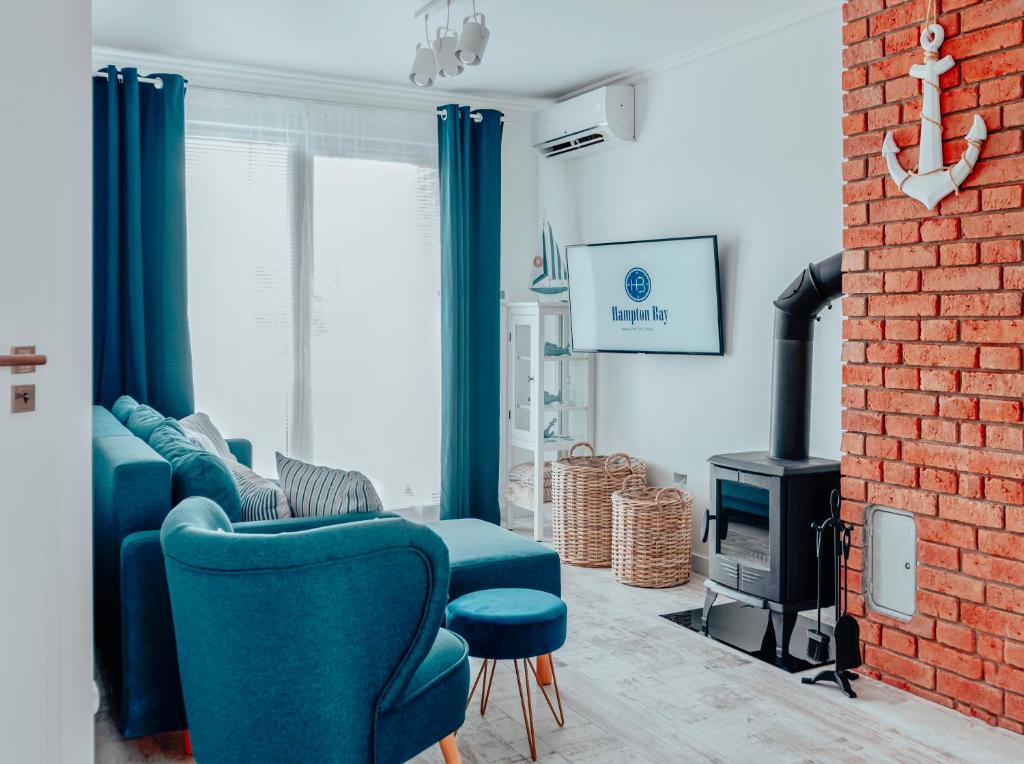 uma sala de estar com cadeiras azuis e uma parede de tijolos em Apartament Hampton Bay em Jantar