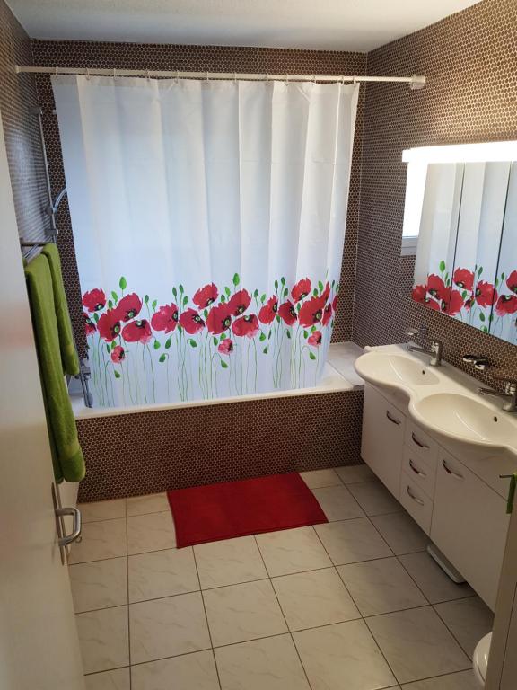 een badkamer met een douchegordijn met rode bloemen bij Gästehaus Luma in Egerkingen