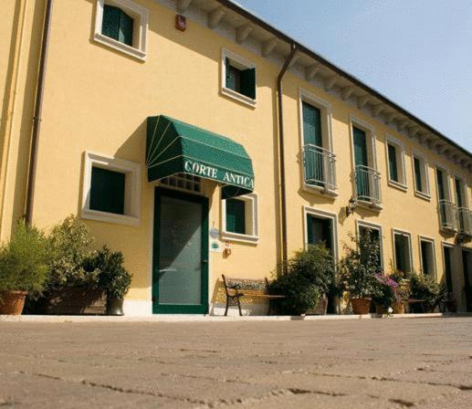 un bâtiment avec une porte verte devant lui dans l'établissement Albergo Corte Antica, à Villafranca di Verona