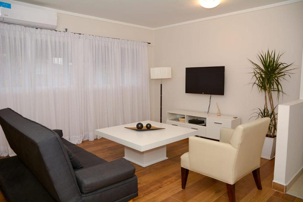 a living room with a couch and a table and a tv at Petit Apart Villa Regina in Villa Regina