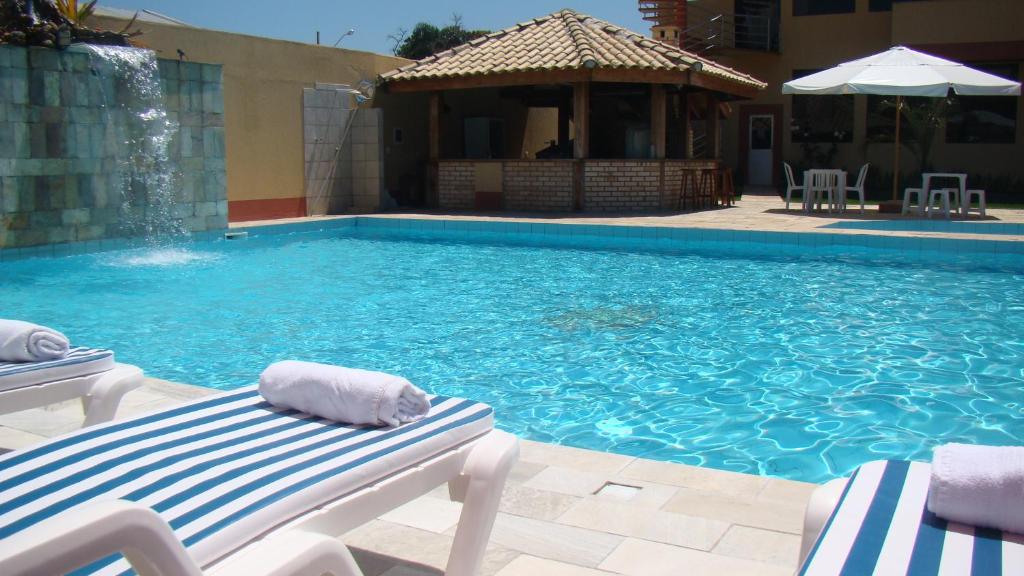 a swimming pool with two lounge chairs and a gazebo at Pousada Vale Del Sol in Bombinhas