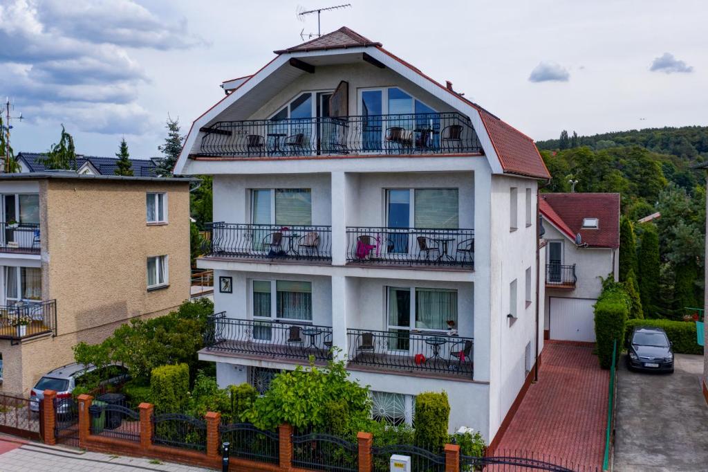 un edificio de apartamentos blanco con balcones y árboles en Willa Sarenka en Międzyzdroje