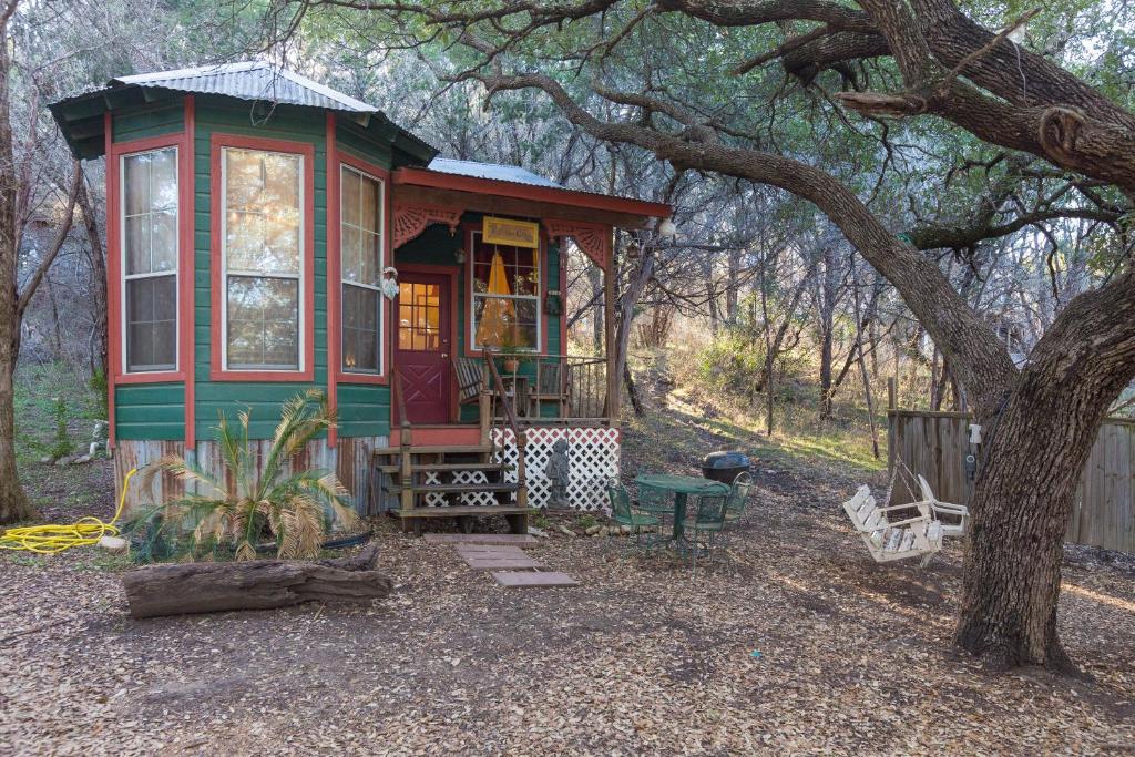 a green and red tiny house in a forest at The Victorian Cottage at Creekside Camp & Cabins in Marble Falls