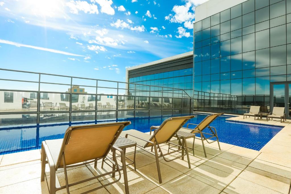 balkon z krzesłami i basen w budynku w obiekcie TRYP By Wyndham Ribeirão Preto w mieście Ribeirão Preto