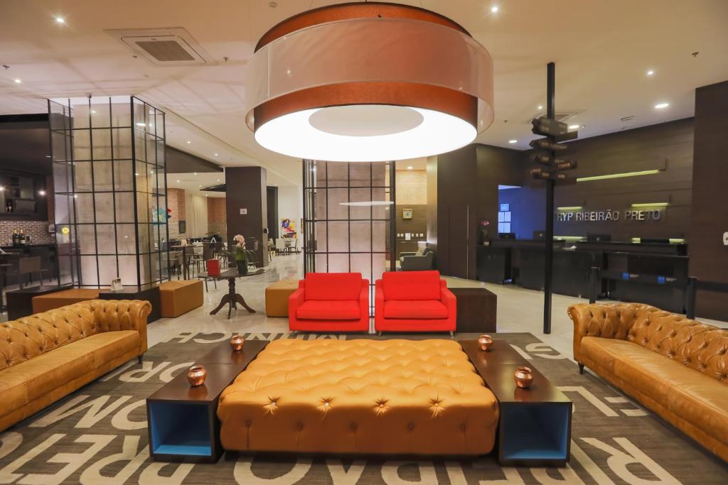 a lobby with a couch and two red chairs at TRYP By Wyndham Ribeirão Preto in Ribeirão Preto