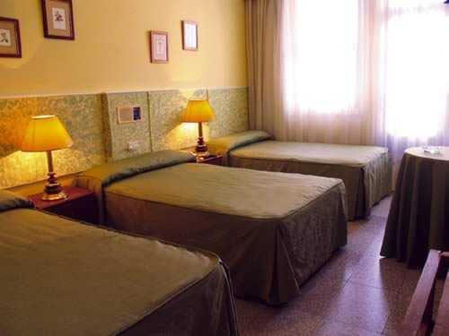 a hotel room with three beds and a window at Hotel Casablanca Vigo in Vigo