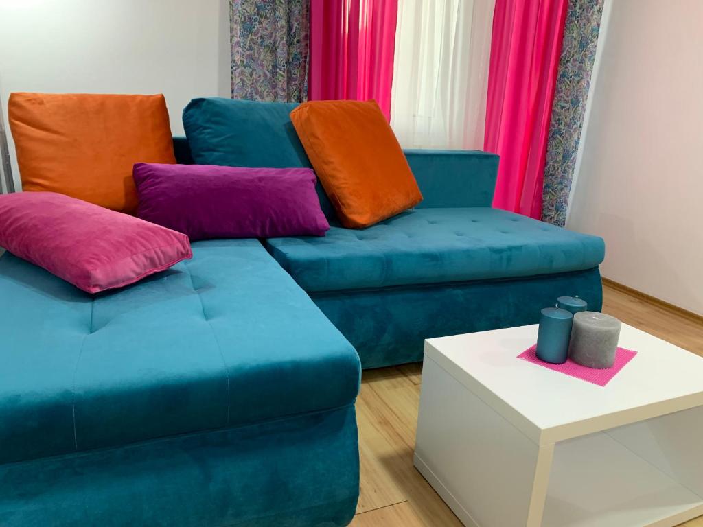 a living room with a blue couch and colorful pillows at La Apartamento Centroom in Jagodina
