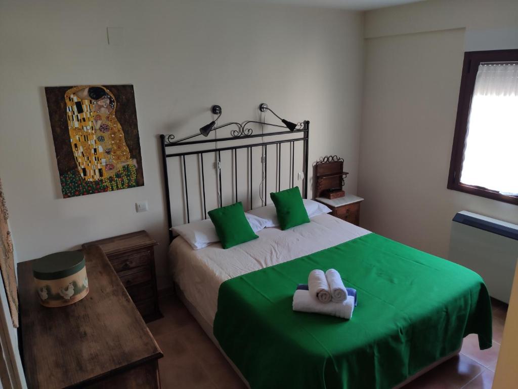 Schlafzimmer mit einem Bett mit grüner Bettwäsche und Handtüchern in der Unterkunft VUT Casa Helen in Avila