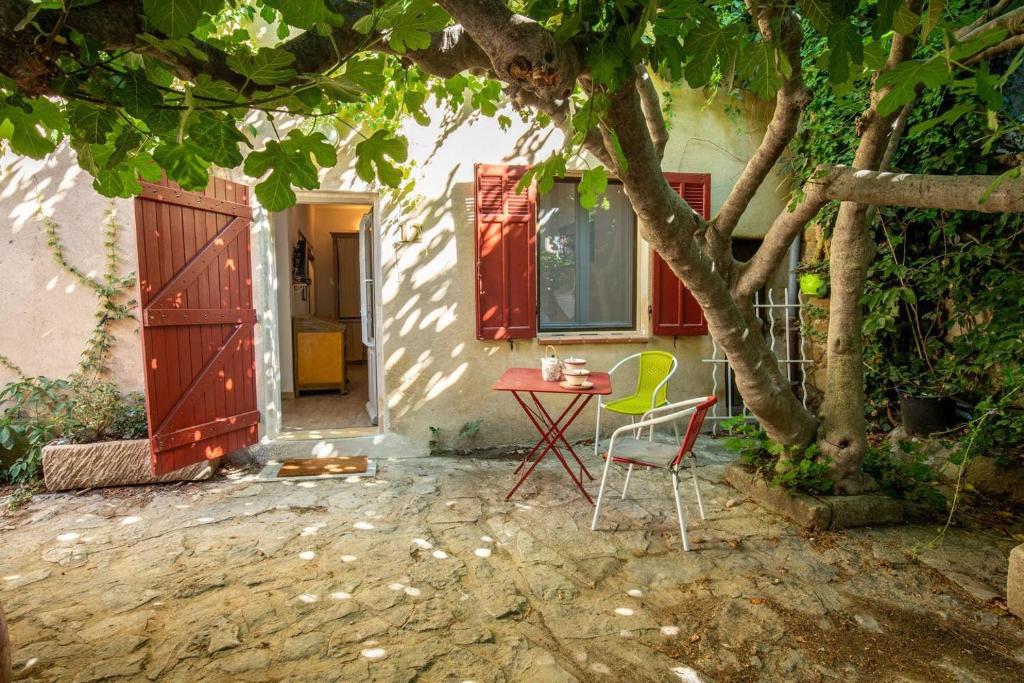 a table and chairs in front of a house with a tree at Havre de paix en Provence in Lauris