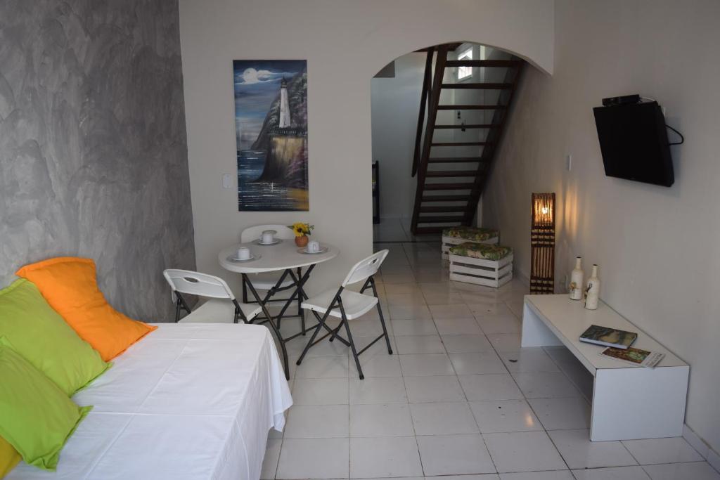 Flat Vila Aju في أراكاجو: غرفة معيشة مع سرير وطاولة وكراسي