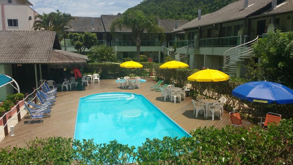 a swimming pool with tables and chairs and umbrellas at Pousada Morada da Praia in Bombinhas