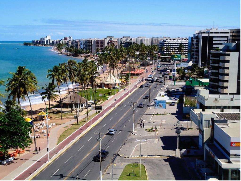 una calle de la ciudad con palmeras y el océano en Apartamento Beira Mar Maceió, en Maceió