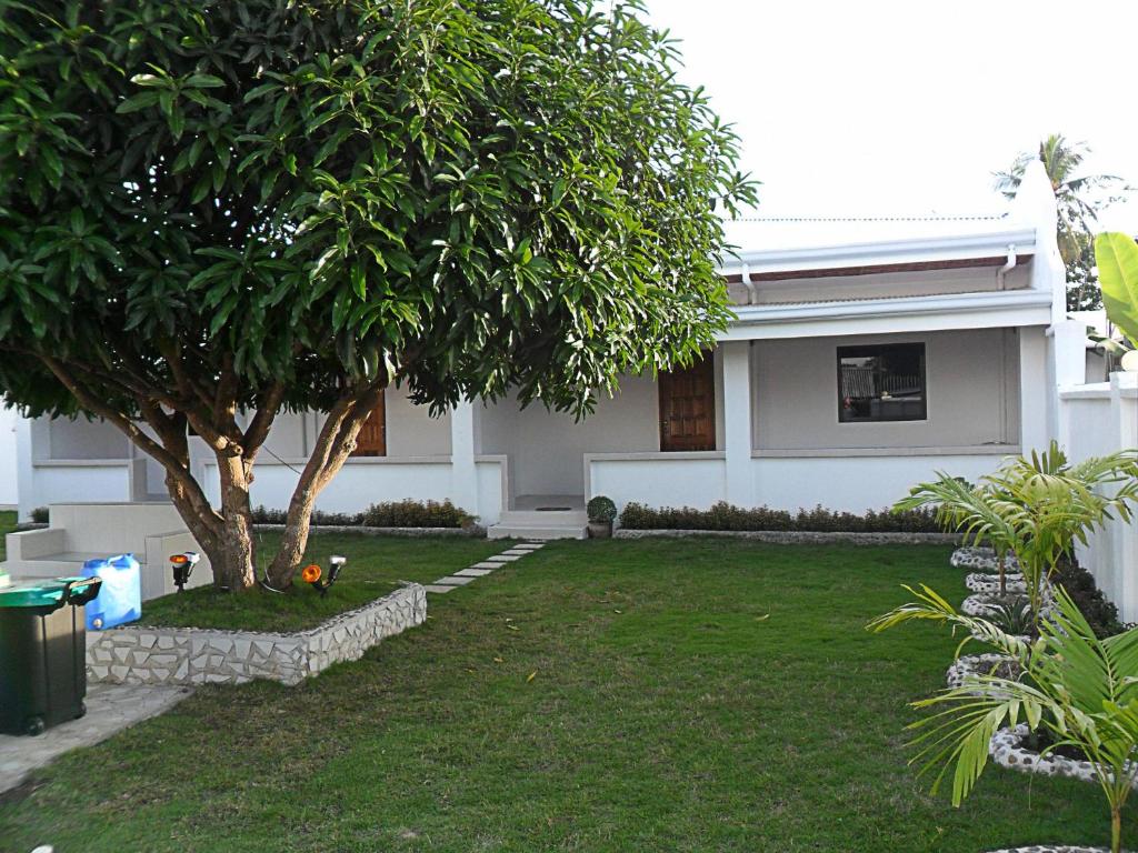 una casa blanca con un árbol en el patio en Jasmin's Room Rental en Moalboal