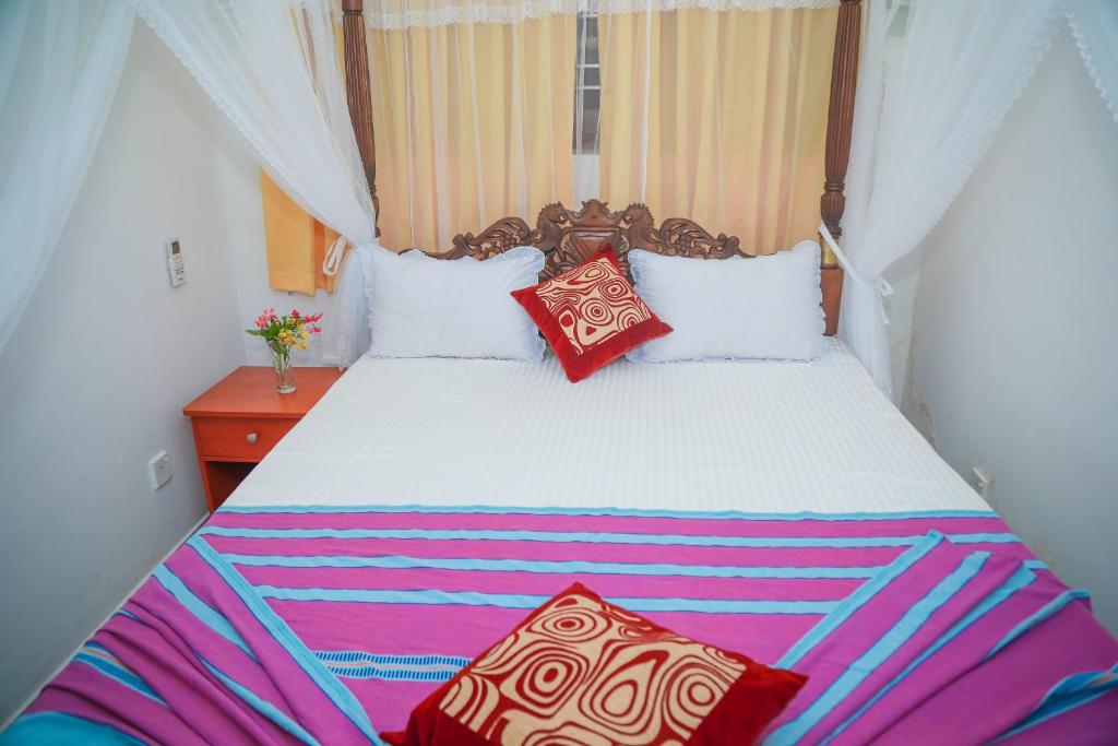 a bedroom with a large bed with red pillows at Hasaranga Holiday House in Hikkaduwa