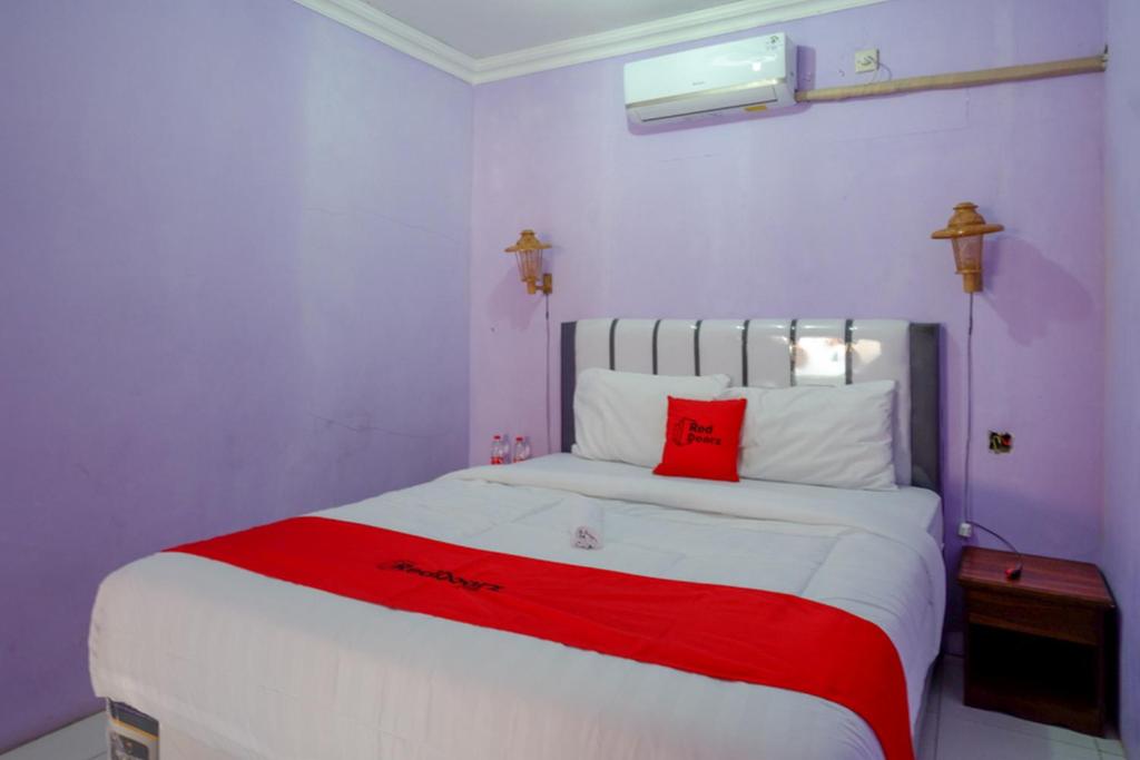 a bedroom with a large white bed with a red blanket at RedDoorz near Goa Jatijajar 2 in Kebumen