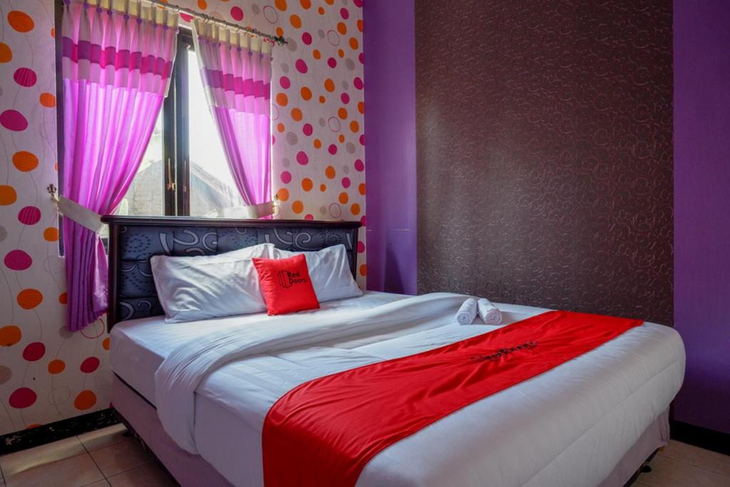 ein Schlafzimmer mit einem großen Bett mit lila und roten Laken in der Unterkunft RedDoorz near RSUD Kebumen in Kebumen