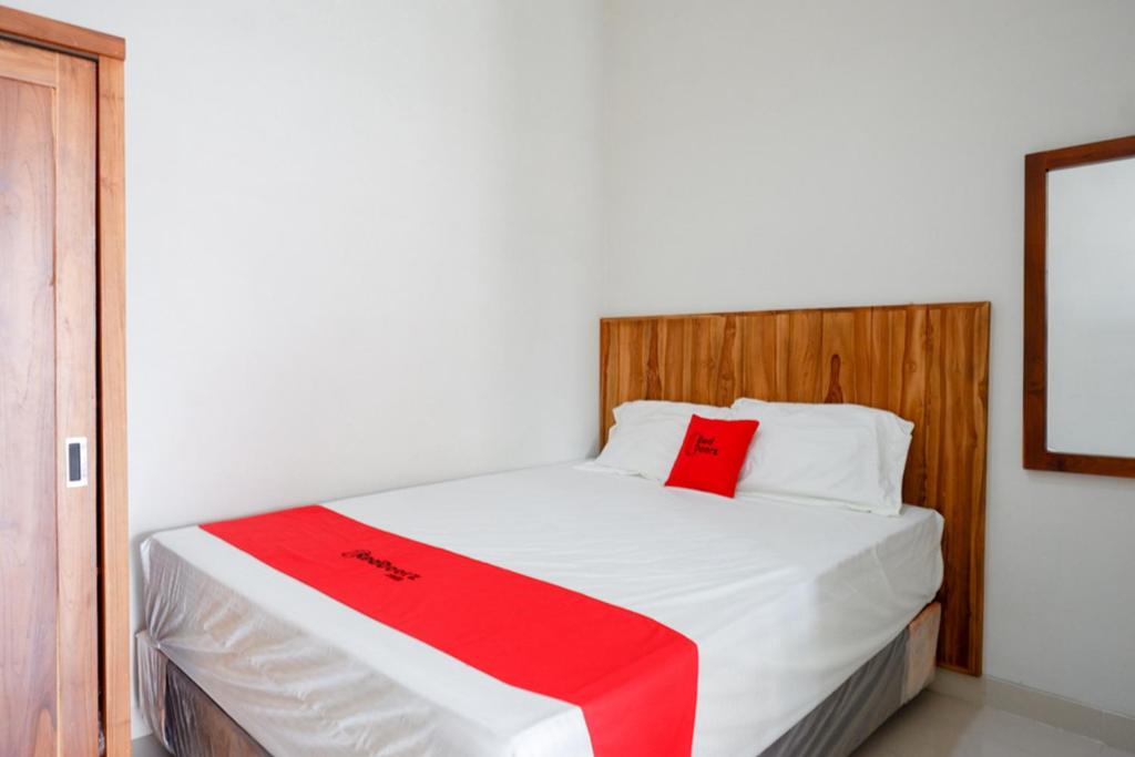 Un dormitorio con una cama blanca con una manta roja. en RedDoorz Plus Syariah near Stasiun Tegal 2 en Tegal