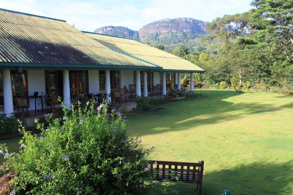 una casa con panchina e montagne sullo sfondo di Jungle Tide a Kandy