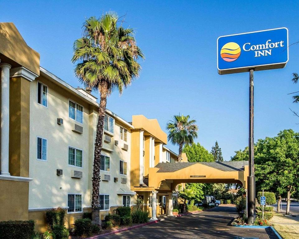 a sign in front of a hotel with a palm tree at Comfort Inn Modesto in Modesto