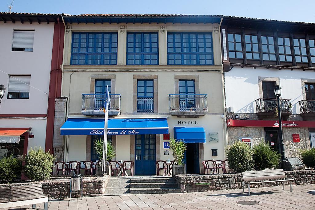 a building with a blue door and chairs in front of it at Hotel Cuevas Del Mar in Nueva de Llanes