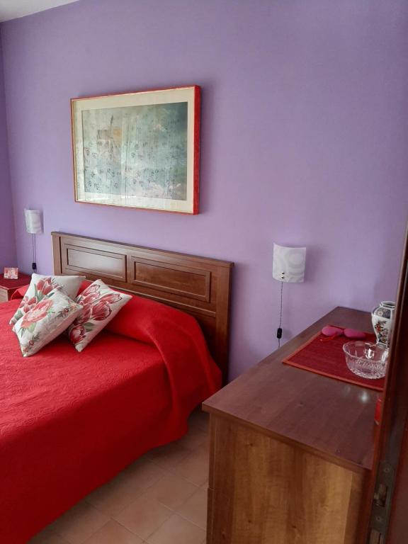 Il Melograno في بونتريمولي: غرفة نوم بجدران ارجوانية وسرير احمر وطاولة
