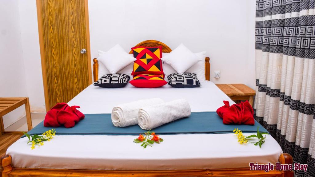 a bedroom with a bed with red and white pillows at Triangle Home Stay in Dambulla
