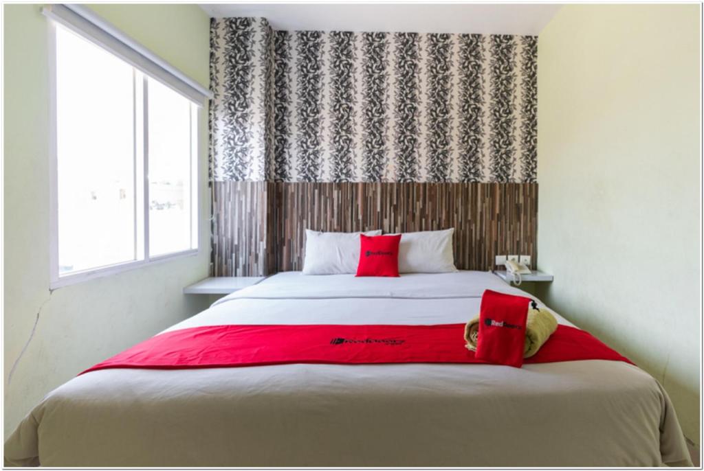 a bedroom with a large bed with red pillows at RedDoorz Plus at Hertasning Area Makassar in Makassar