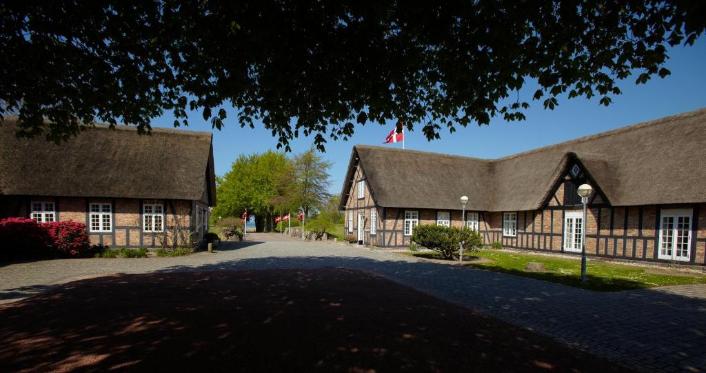 an old building with a gambrel roof and a road at Gl. Avernæs Sinatur Hotel & Konference in Ebberup