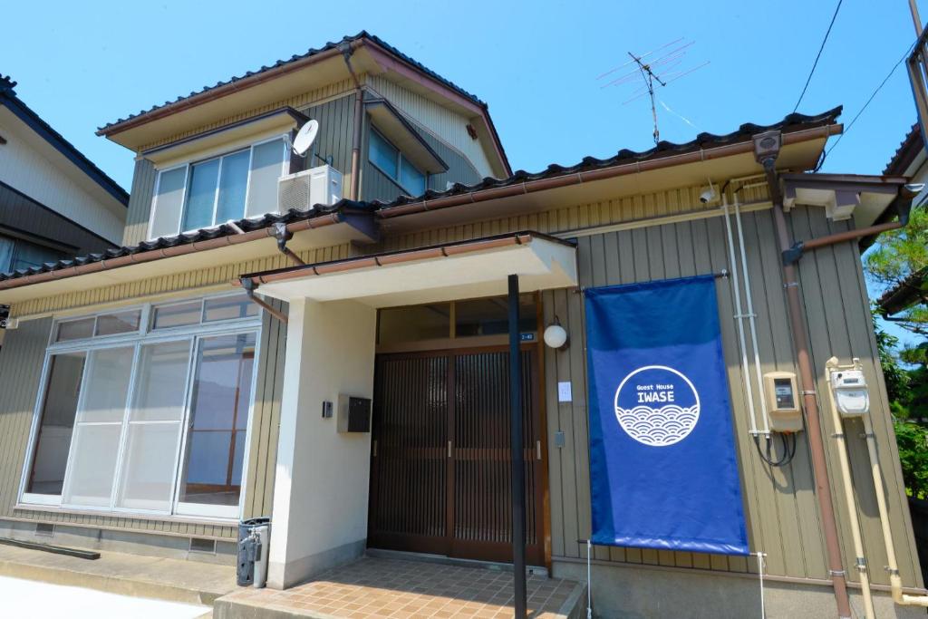 una casa con una pancarta azul en la puerta en Guesthouse Iwase, en Toyama