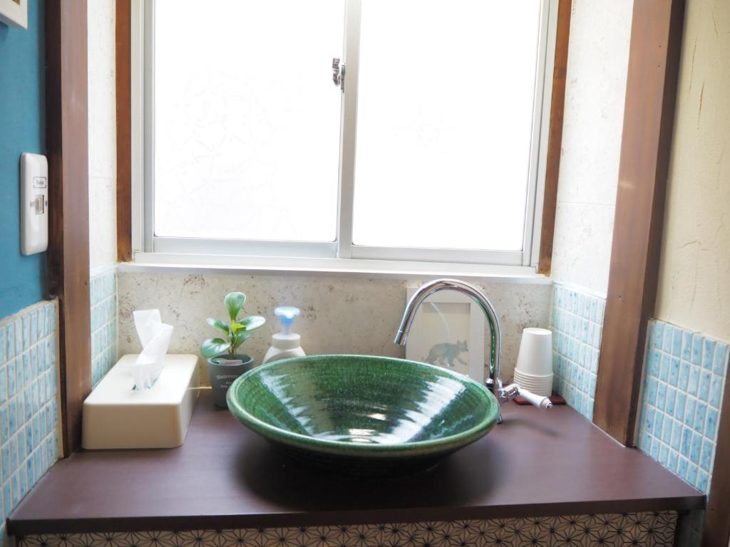 a bathroom sink with a green glass bowl at Guesthouse Iwase in Toyama