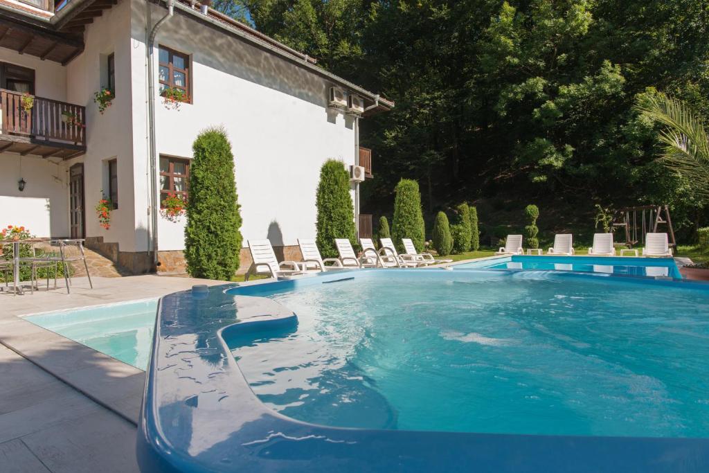 una piscina en un patio con sillas y un edificio en Family Hotel Bile, en Beli Osŭm