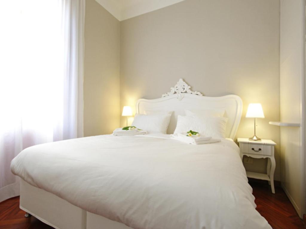 uma cama branca com uma cabeceira branca e uma janela em Mercalli 1 em Milão